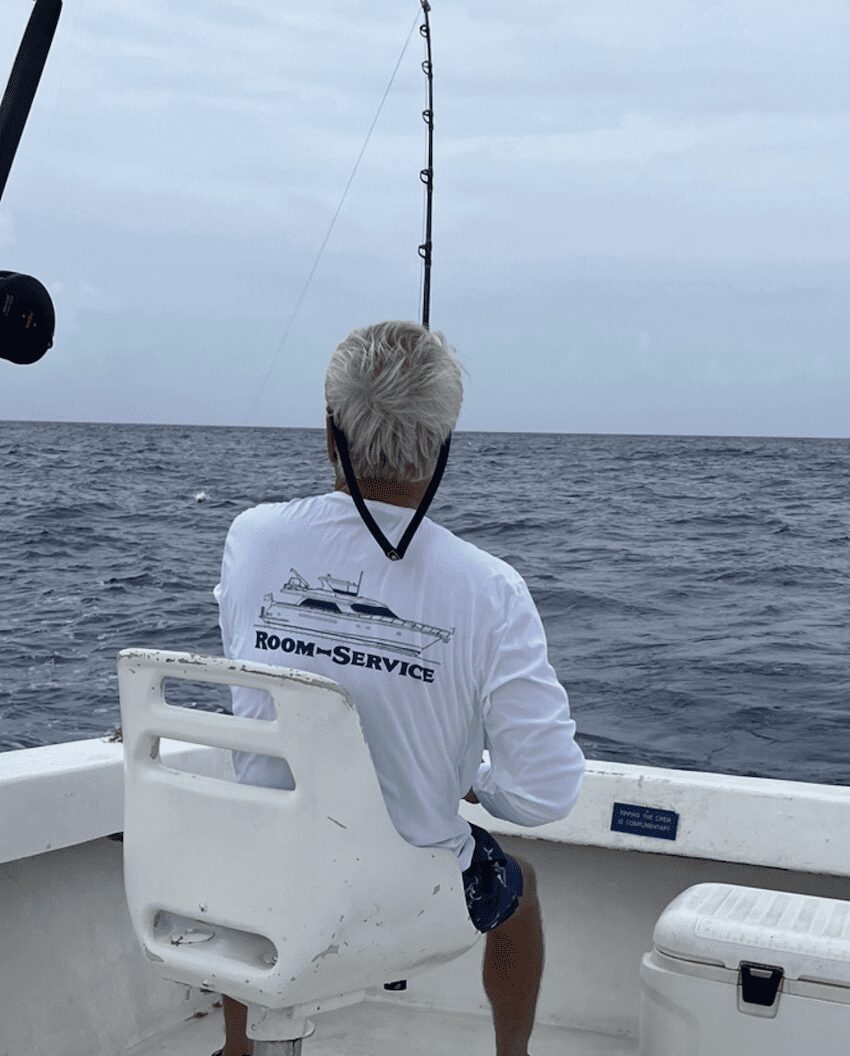 Person fishing on a boat in the ocean with overcast skies.